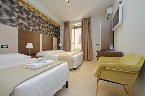 a hotel room with two beds and a yellow chair at Roma Suite Centro in Rome
