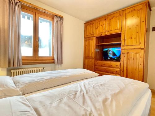 una camera con un letto e un comò con una televisione di Chalet Rododendro a Livigno