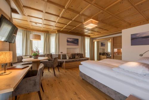 a bedroom with a large bed and a living room at Hotel Unterwirt in Reit im Winkl