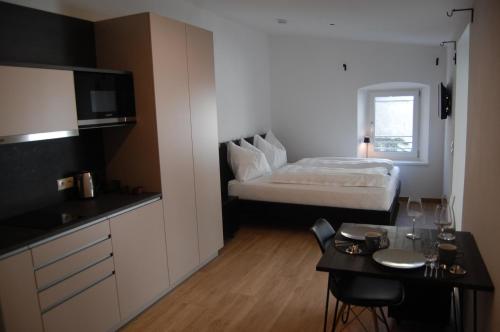 a room with a bed and a table and a kitchen at myQuartier - Central City DeLuxe Apartments in Innsbruck