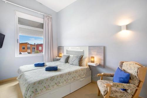 a bedroom with a bed and a chair and a window at Duplex Pozo Canary in Pozo Izquierdo
