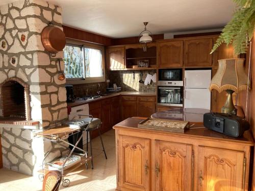 eine Küche mit Holzschränken und einem Steinkamin in der Unterkunft Villa 4* Proche centre et plage. Animaux bienvenus in Meschers-sur-Gironde
