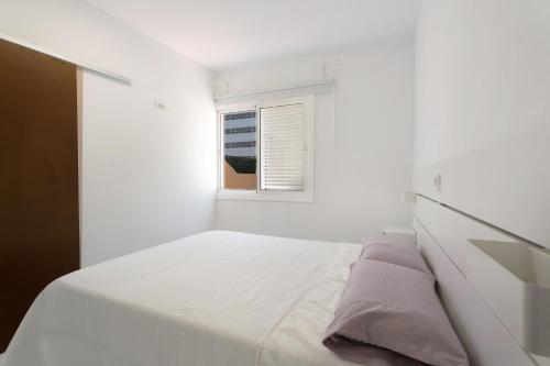een witte slaapkamer met een bed en een raam bij Apartamento El Médano Marineda in Granadilla de Abona