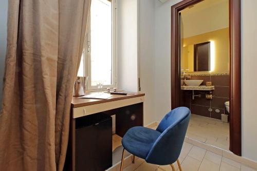 baño con silla azul, escritorio y espejo en Roma Suite Centro, en Roma