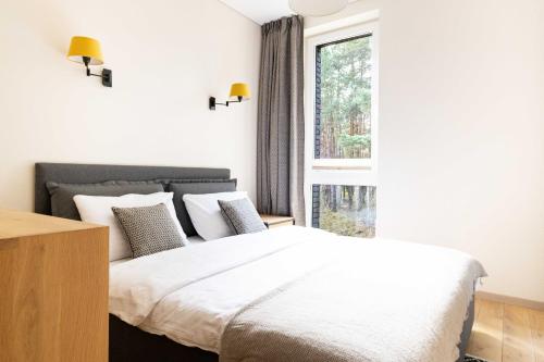 um quarto com uma cama grande e uma janela em Pine Forest View Apt With Balcony, By Cohost em Palanga