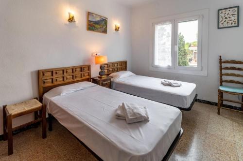 une chambre avec deux lits et une chaise et une fenêtre dans l'établissement Carboneres 461 - Apartamento con terraza y vistas, à Llançà