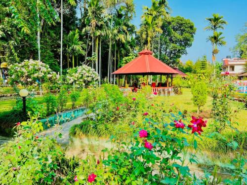a garden with a gazebo with flowers and a pond at Hotel Hermitage in Sauraha