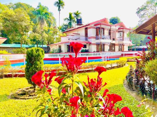 a house with red flowers in front of it at Hotel Hermitage in Sauraha