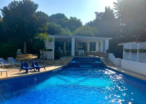 a swimming pool with two blue chairs next to a house at Villa Aurea in Ispica