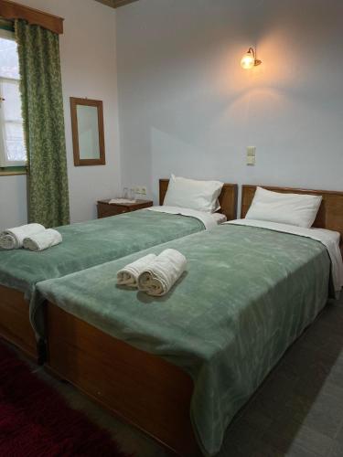 Dos camas en una habitación de hotel con toallas. en Hotel Zagori, en Skamnéllion