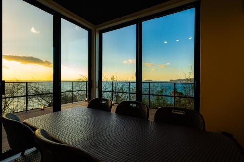 a table with chairs in a room with windows at theView 南房総 in Ichibu