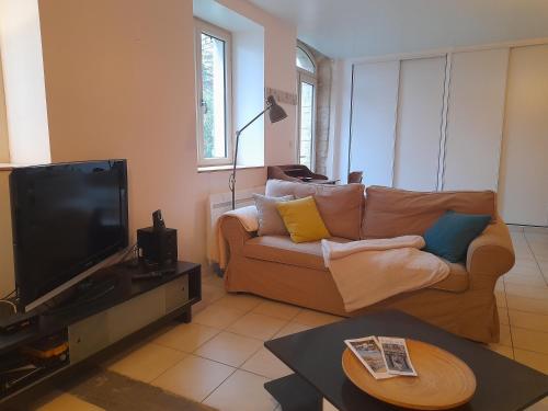 un salon avec un canapé et une télévision dans l'établissement Une pause près de Pégasus Bridge, à Ranville