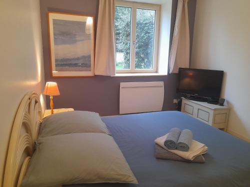 - une chambre avec un lit, 2 serviettes et une télévision dans l'établissement Une pause près de Pégasus Bridge, à Ranville