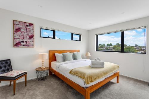 a bedroom with a bed and two windows at Sleek Vista Townhouse with deck and air-con in Auckland
