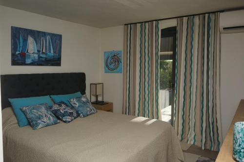 a bedroom with a bed with blue pillows and a window at Villa les Cades in Sainte-Maxime