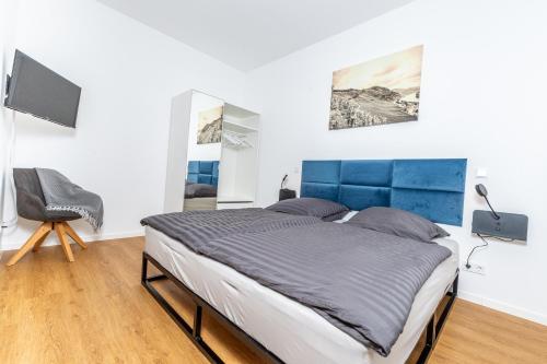 Schlafzimmer mit einem großen Bett mit blauem Kopfteil in der Unterkunft Apartment Weingut Dr Hermann I in Erden