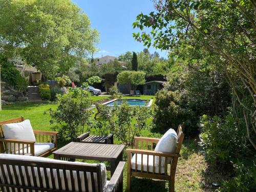 three wooden benches and a table in a yard at Charmante dépendance avec piscine en Provence in Le Puy-Sainte-Réparade