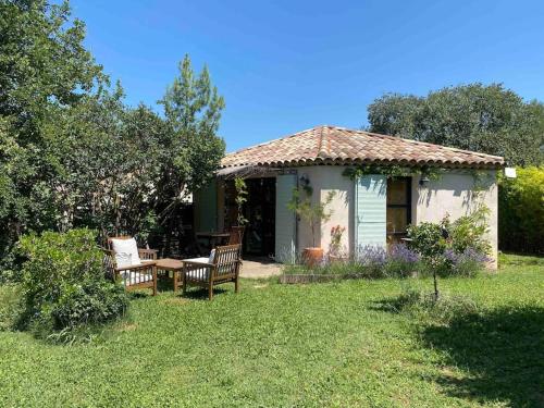 a small house with a table and chairs in the yard at Charmante dépendance avec piscine en Provence in Le Puy-Sainte-Réparade