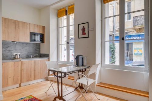 une cuisine avec une table et des chaises dans une pièce dans l'établissement Elegant apartment Bordeaux center, à Bordeaux