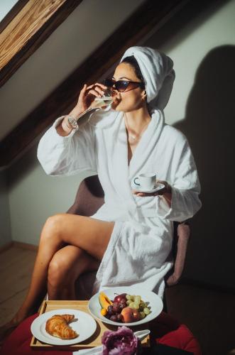 a woman sitting in a robe drinking a cup of coffee at Romantik Spa Hotel Elixhauser Wirt in Elixhausen