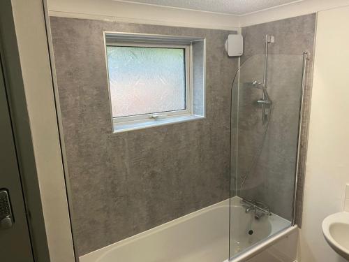 uma casa de banho com um chuveiro, uma banheira e uma janela. em Brays View em Ely
