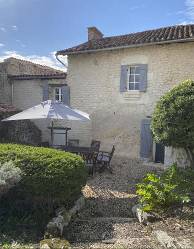 une table avec un parasol devant une maison dans l'établissement Maison d'Amis, à Salles-Lavalette
