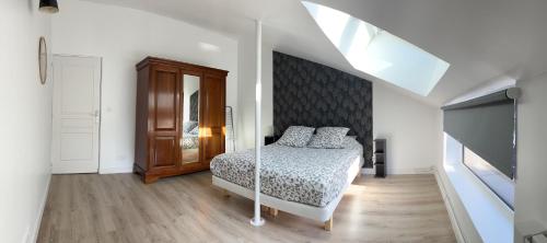 a white bedroom with a bed and a large window at LE FAUBOURG SAINT MARTIN in Senlis