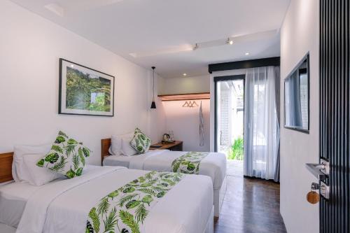two beds in a room with white walls at Chandi Hotel Ubud in Ubud