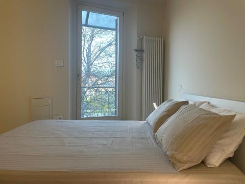 a bedroom with a large white bed with a window at Casa Piccolo Charme e Design nel cuore di Maderno in Toscolano Maderno