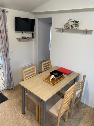une table à manger avec des chaises et une télévision dans l'établissement Mobil Home tout confort idéal pour 4 personnes dans le Domaine de Dugny CAMPING 4 ETOILES, Proche de Blois, du Zoo de beauval et des Châteaux de la Loire, à Onzain