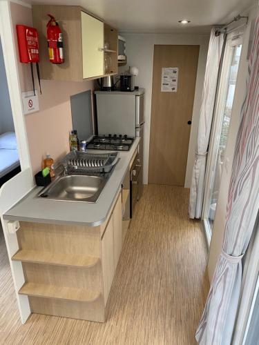 a small kitchen with a sink and a stove at Mobil Home tout confort idéal pour 4 personnes dans le Domaine de Dugny CAMPING 4 ETOILES, Proche de Blois, du Zoo de beauval et des Châteaux de la Loire in Onzain