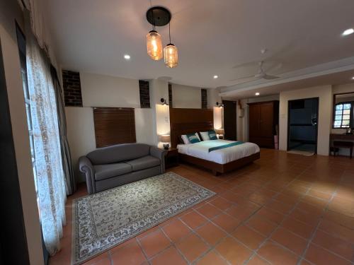 um quarto com uma cama e um sofá num quarto em Botanica Mansion em Balik Pulau