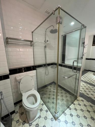 a bathroom with a toilet and a glass shower at Botanica Mansion in Balik Pulau