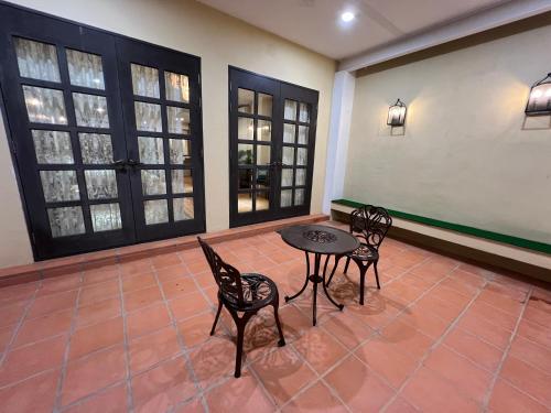 eine Terrasse mit einem Tisch, Stühlen und Fenstern in der Unterkunft Botanica Mansion in Balik Pulau