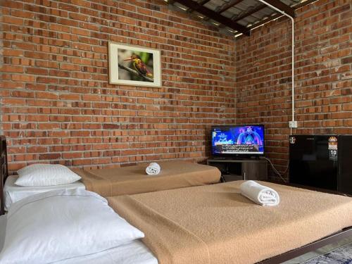 duas camas num quarto com uma parede de tijolos em MyDusun Chalet, Taiping, Perak, Malaysia em Taiping