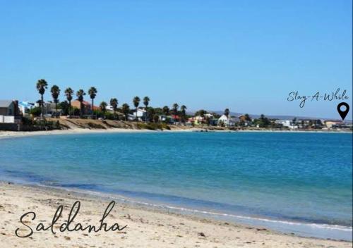 a beach with blue water and palm trees in the background at Stay-A-While by Ustay in Saldanha