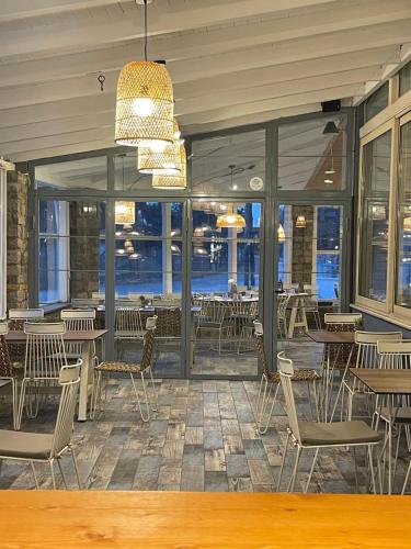a restaurant with tables and chairs and windows at Isalos Suites in Néa Péramos