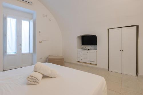 a white bedroom with a white bed and a television at La Loggetta in Ugento