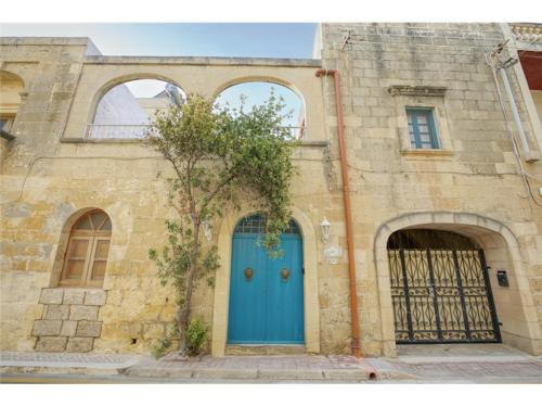 un bâtiment avec une porte bleue et deux arches dans l'établissement Authentic 4 Br Gozitan Farmhouse with Private Pool by 360 Estates, à L-Għarb