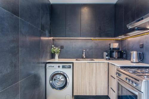 a kitchen with a washing machine and a sink at Holiday Studio In JVC 2302, Dubai in Dubai