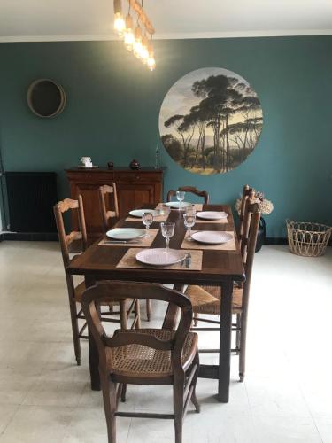 une table à manger avec des chaises et une plaque murale dans l'établissement Entre verre et mer, à Dargnies