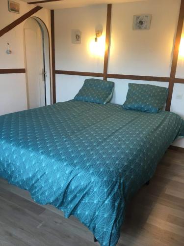 - un lit avec une couette bleue dans l'établissement Entre verre et mer, à Dargnies