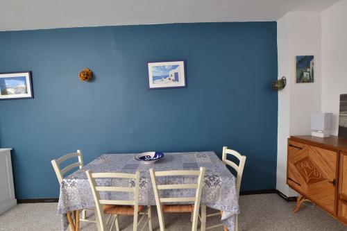 une salle à manger avec une table et un mur bleu dans l'établissement Vue mer depuis l'altitude zéro, au Grau-du-Roi