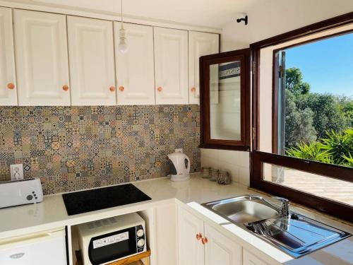 a kitchen with white cabinets and a sink and a window at Self-contained floor of Quinta / Villa in Guia