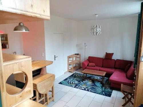 un salon avec un canapé rouge et une table dans l'établissement Appartement avec jardin au calme, à Montreuil