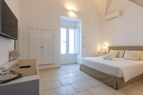 a white bedroom with a bed and a television at La Loggetta in Ugento
