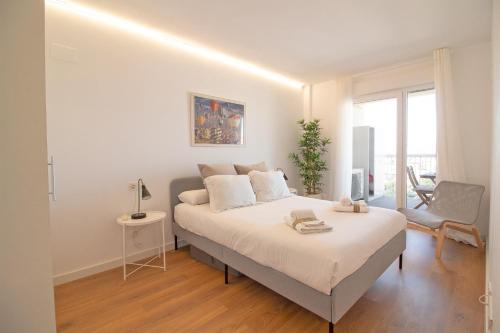1 dormitorio blanco con 1 cama y 1 silla en Global Properties, Moderno apartamento con piscina y terraza en la playa de Canet, en Canet de Berenguer