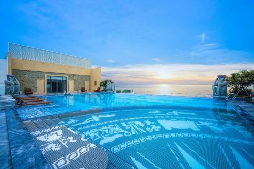 a large swimming pool with the ocean in the background at Apec Mandala Hotel Tuy Hoà in Tuy Hoa