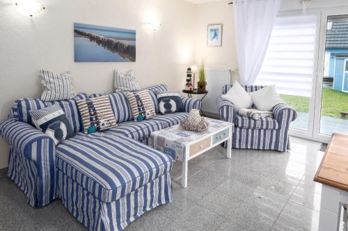 una sala de estar con sofás de rayas azules y blancas y una mesa. en Ferienhaus Kranich, en Pruchten