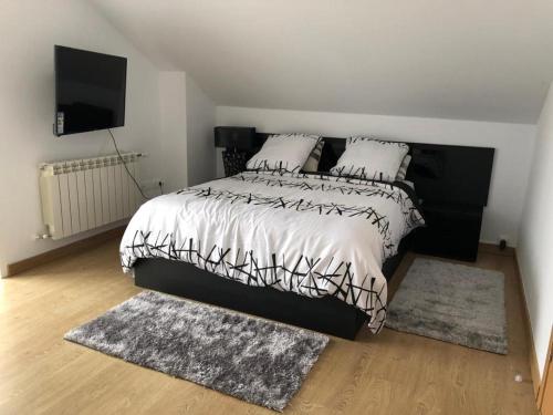 1 dormitorio con 1 cama en blanco y negro con 2 alfombras en Grande Dúplex cerca del Mar, en San Vicente de la Barquera